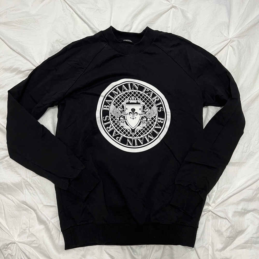 Balmain black crew neck sweater with white velvet medallion.